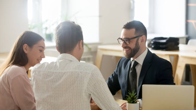 Banking employee smiling and chatting to two customers